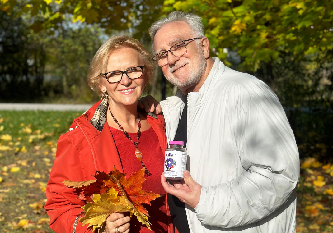 Natural Pharmaceuticals ImuBerin® Starsza para w jesiennym parku z liśćmi i suplementem diety wspierającym odporność.