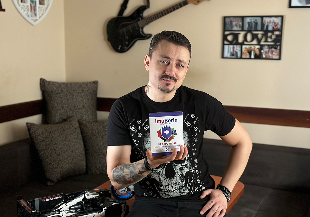 Natural Pharmaceuticals ImuBerin® Mężczyzna w czarnej koszulce prezentuje suplement diety ImuBerin na odporność w przytulnym salonie.